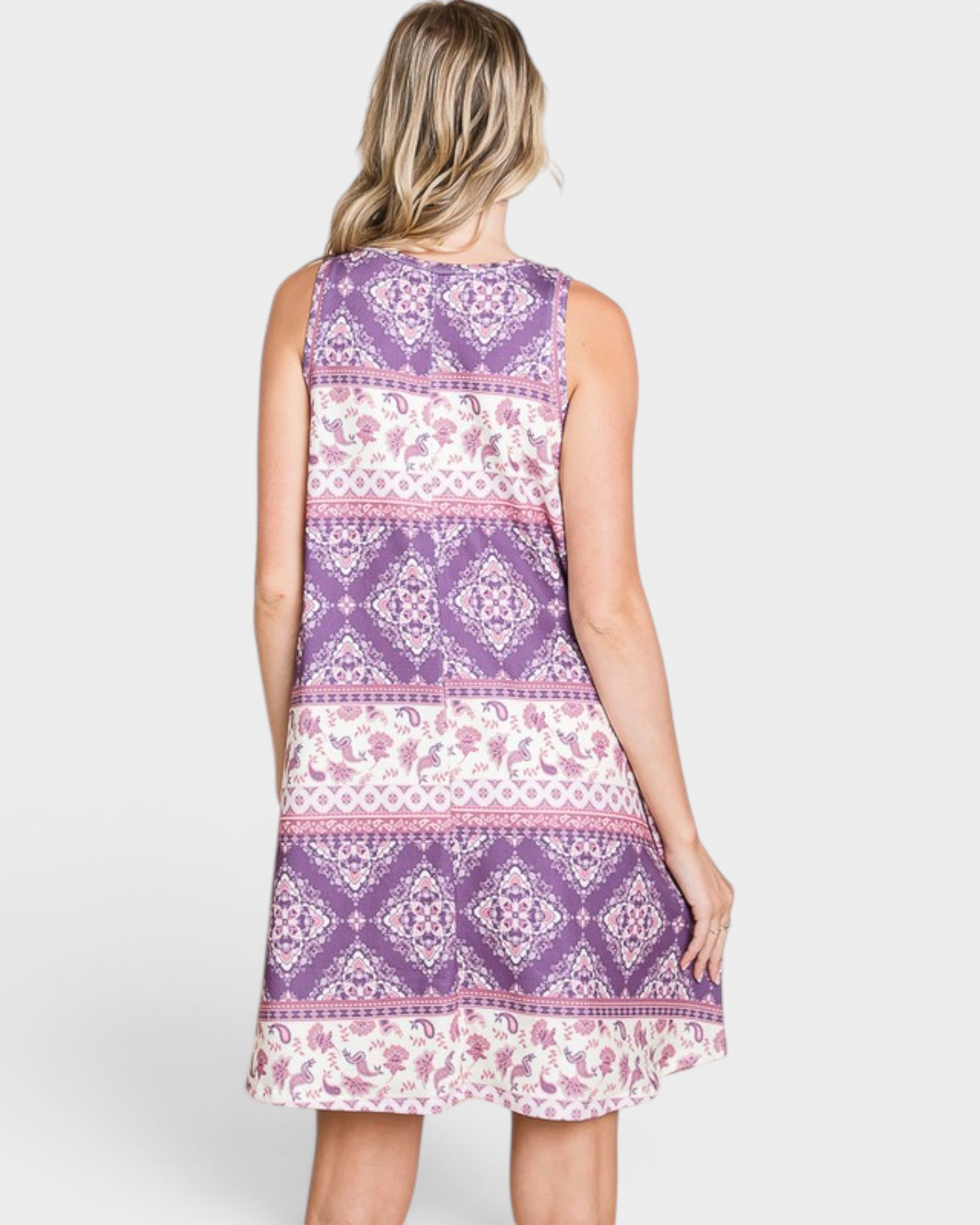 Woman wearing a sleeveless dress with purple and white pattern on a white background