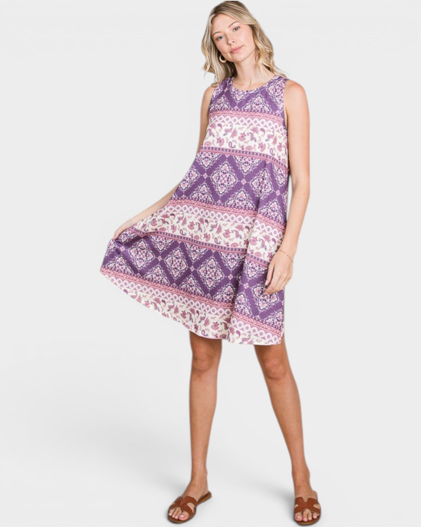 Woman wearing a sleeveless, patterned dress with a white background
