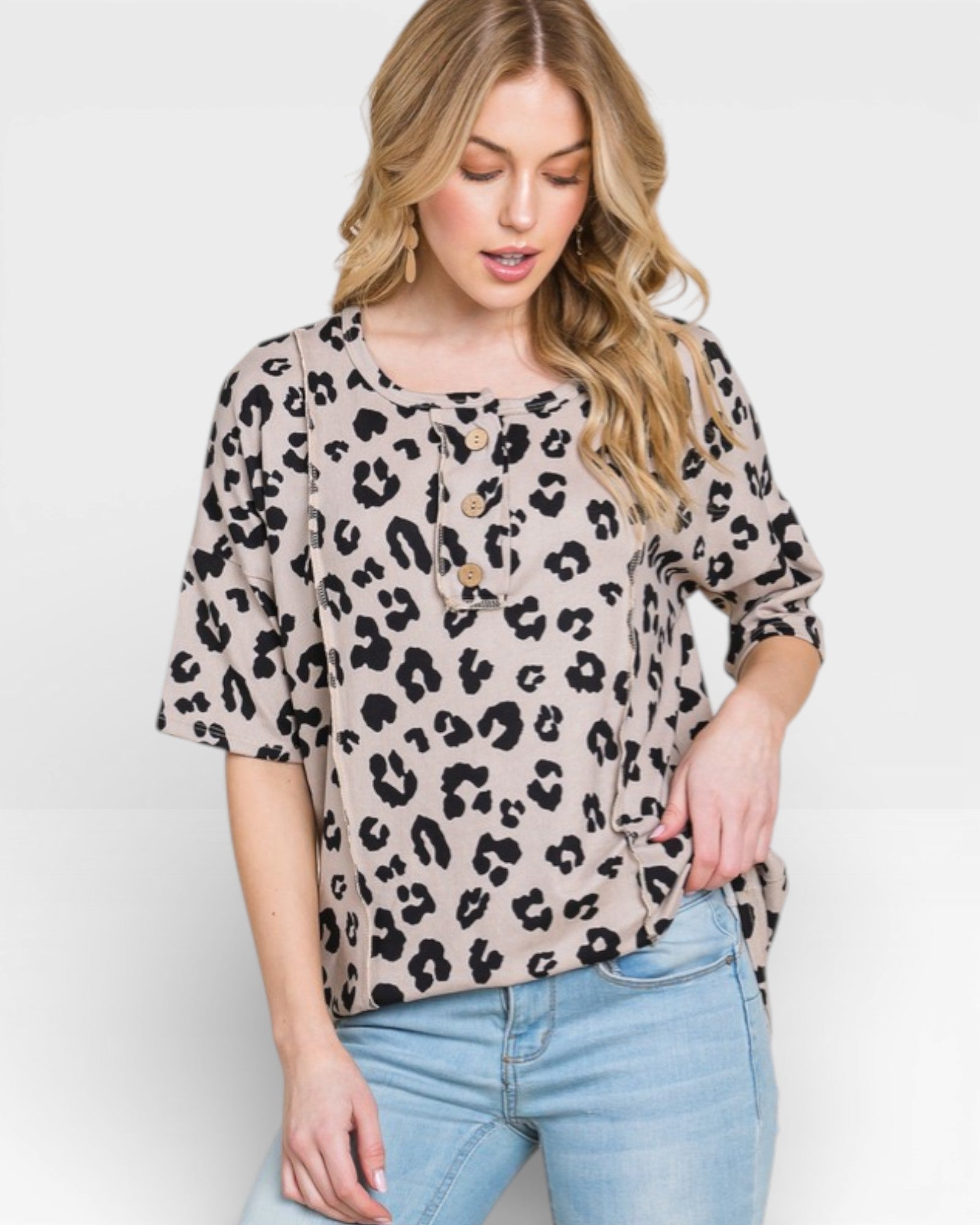 Woman wearing a leopard print top and light blue jeans on a white background