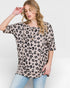 Woman wearing a leopard print top and light blue jeans on a white background