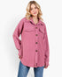A woman modeling a pink textured, long-sleeve button-up shirt jacket with a subtle geometric pattern, paired with blue jeans, against a plain white background.