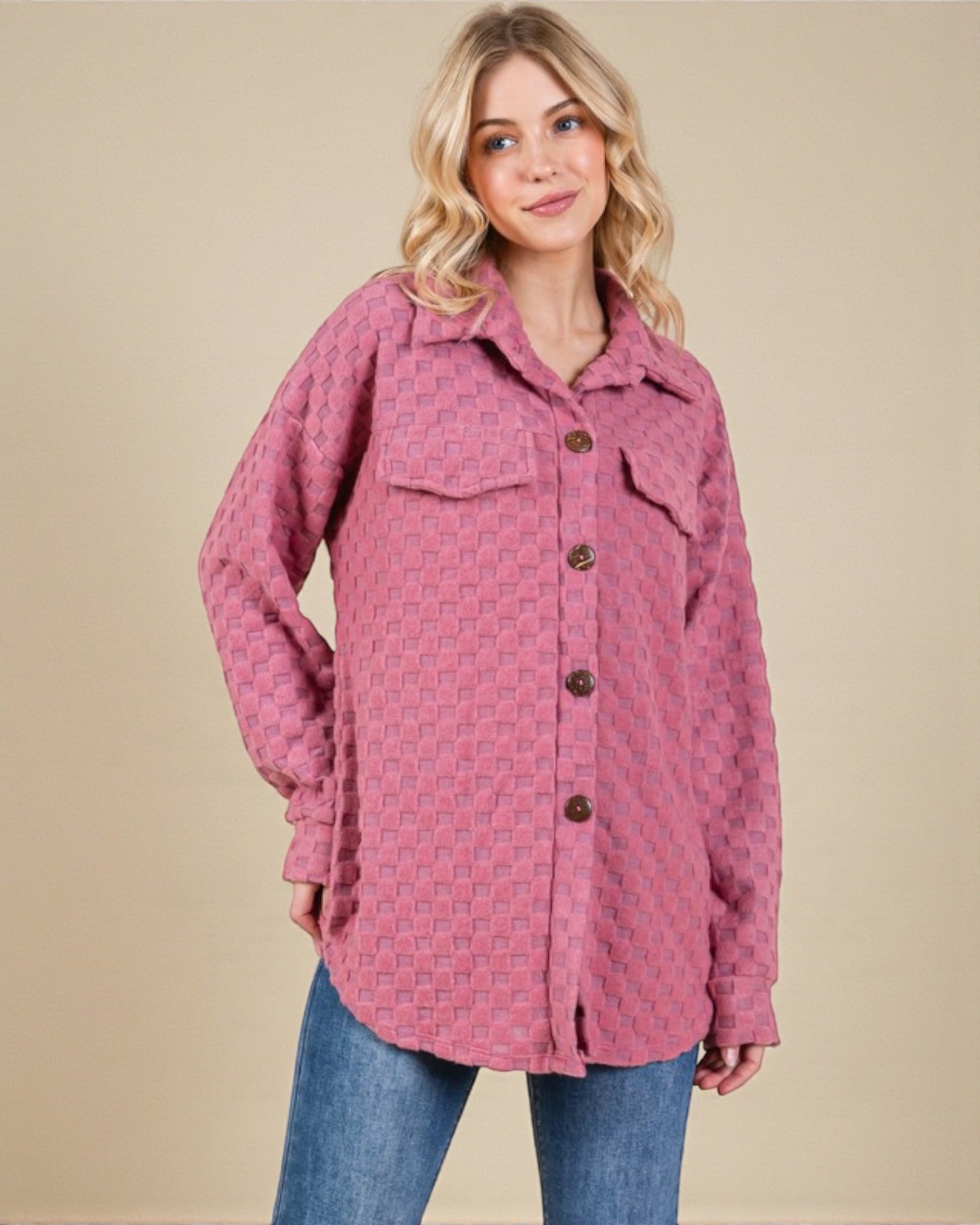 Woman wearing a pink patterned jacket with buttons on a beige background