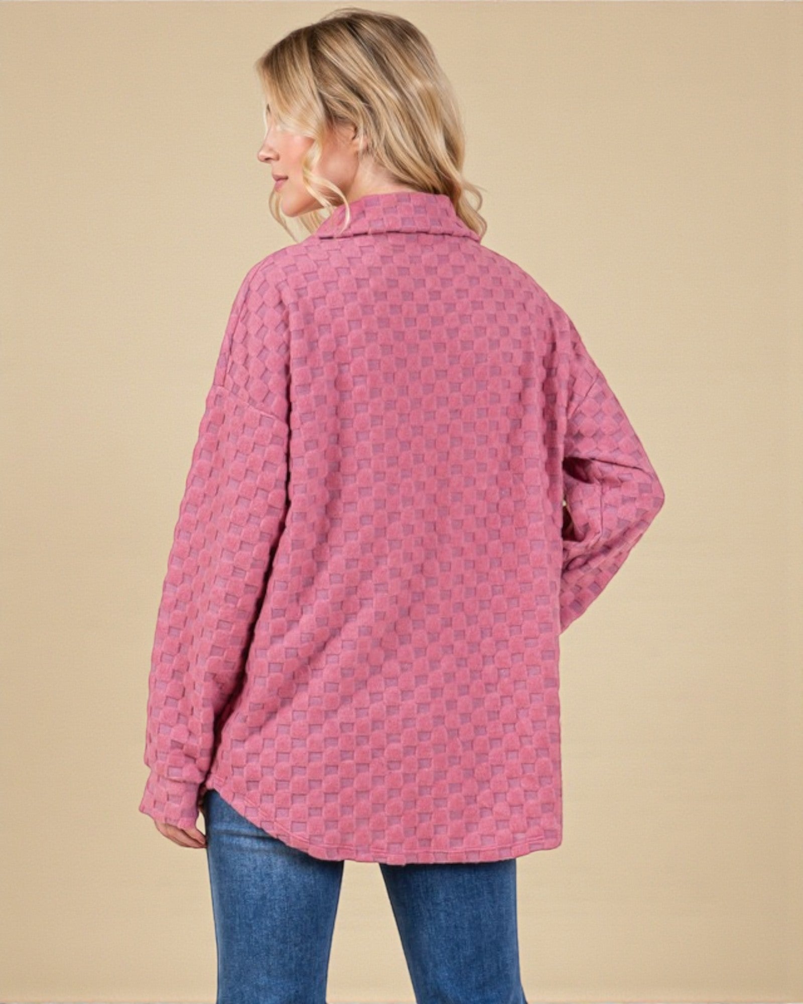 Person wearing a pink patterned shirt against a beige background