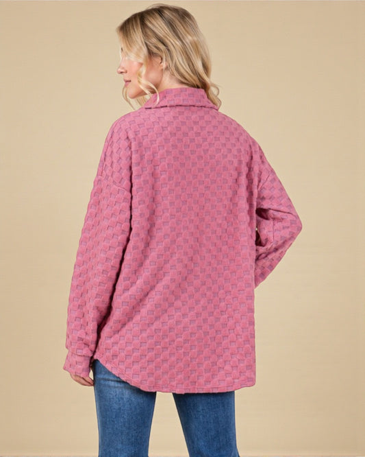 Person wearing a pink patterned shirt against a beige background