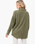 A woman shown from the back wearing a long-sleeve olive green quilted button-up shirt with a subtle geometric pattern, paired with white pants, against a plain white background.