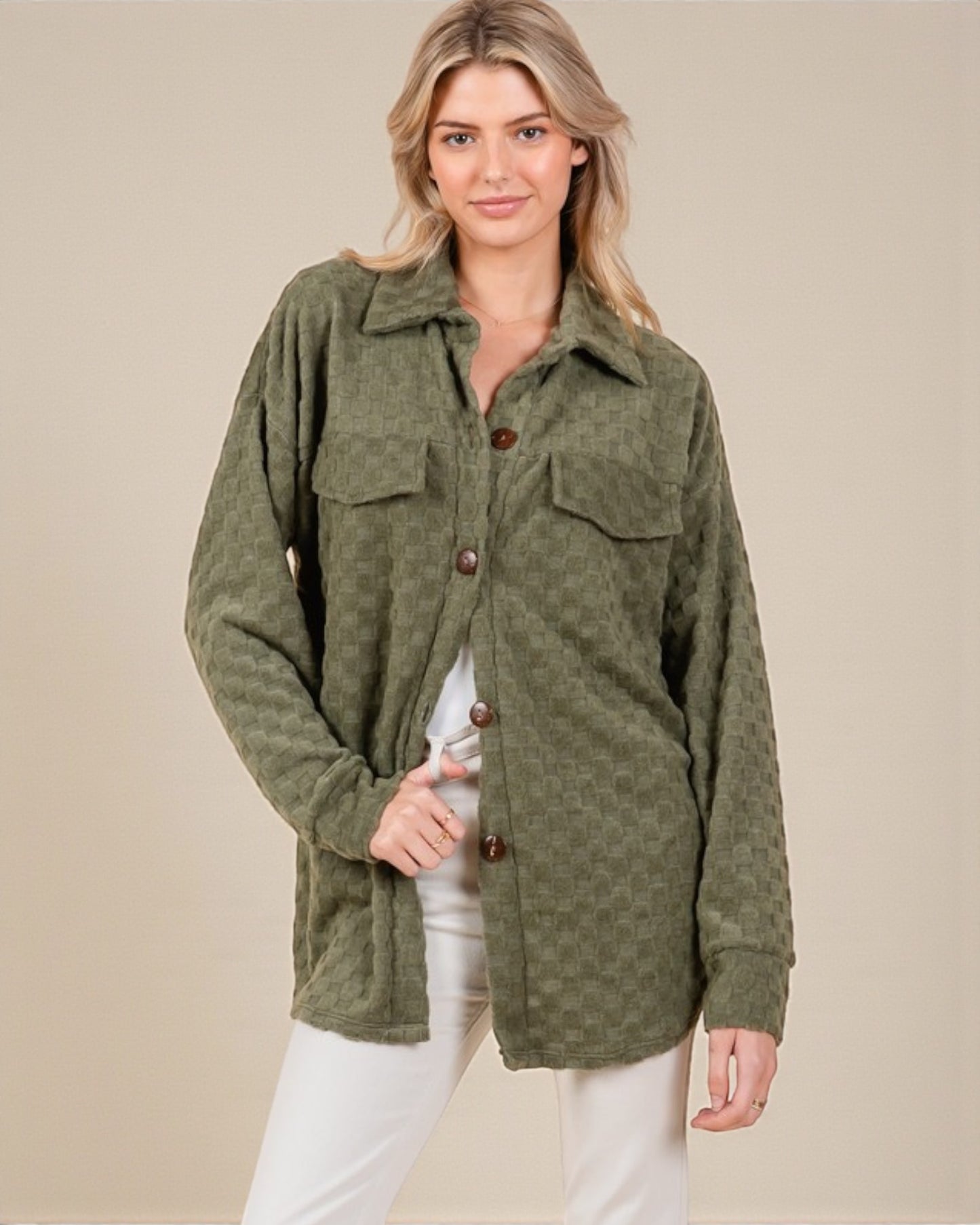 Woman wearing a green jacket with button details on a beige background