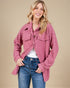 Woman wearing a pink quilted jacket and blue jeans on a beige background