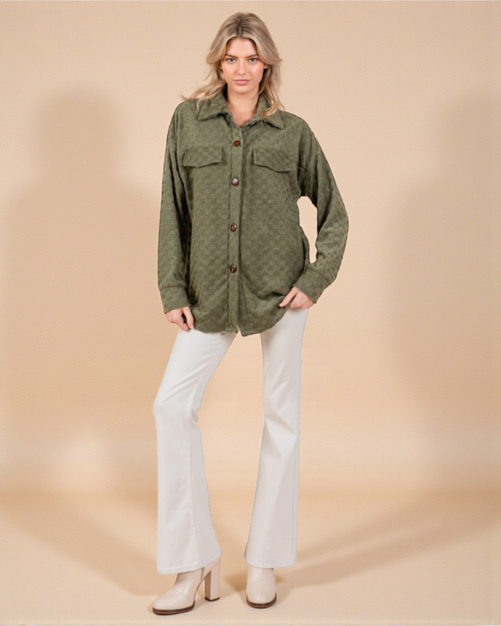 Woman wearing a green shirt and white pants on a beige background