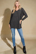 Woman wearing a dark patterned sweater, blue jeans, and black boots on a beige background