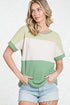 Woman wearing a green and white color-blocked top with denim shorts on a white background