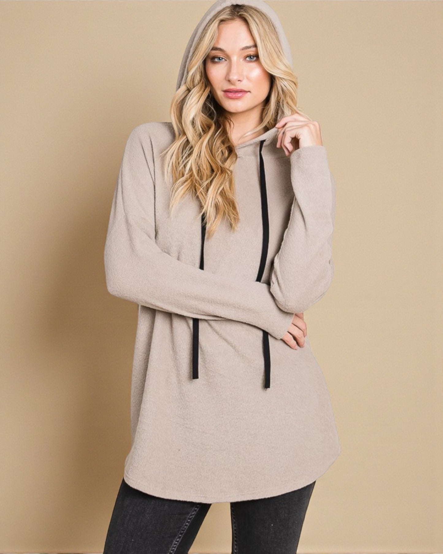 Woman wearing a beige hoodie against a beige background