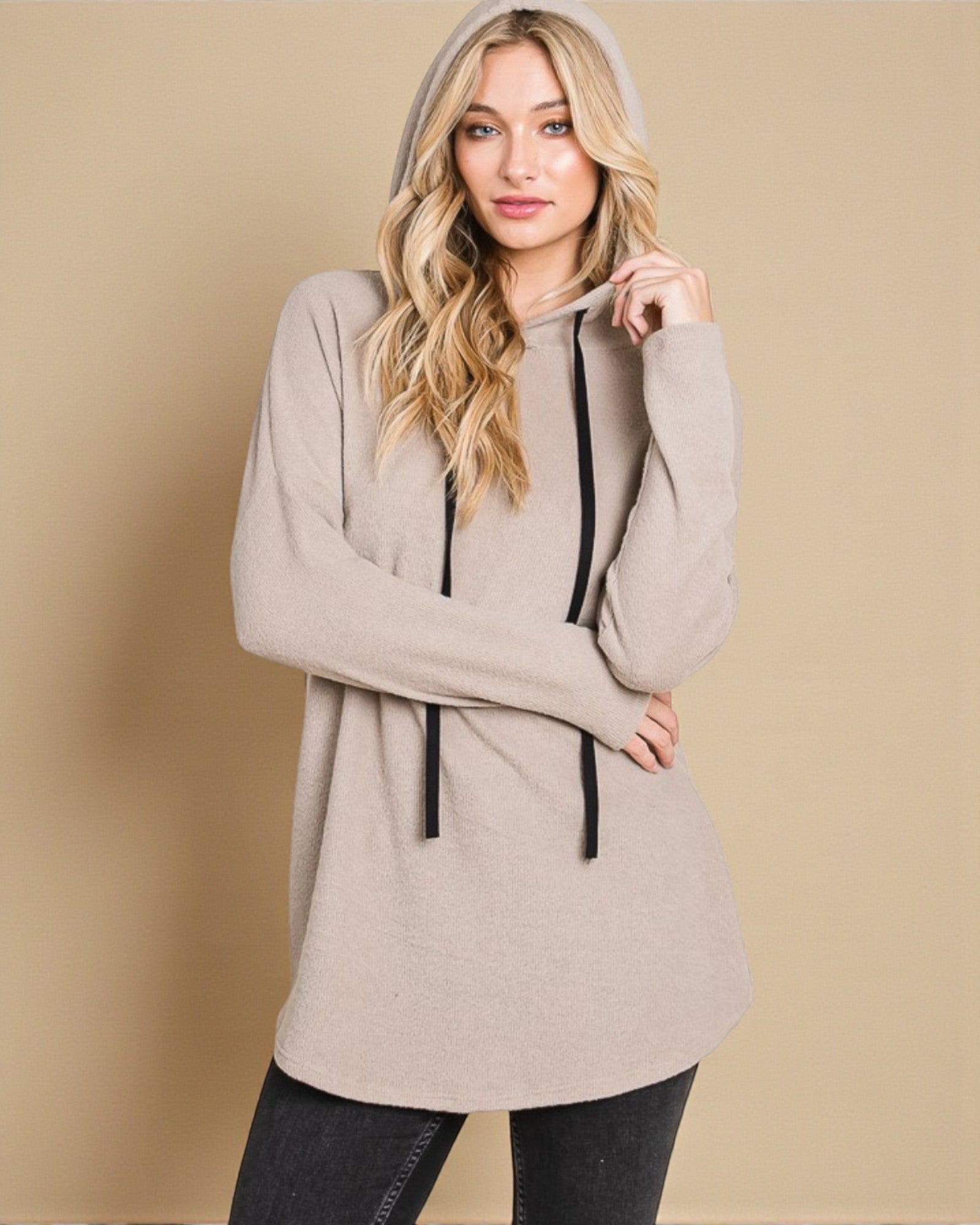 Woman wearing a beige hoodie against a beige background