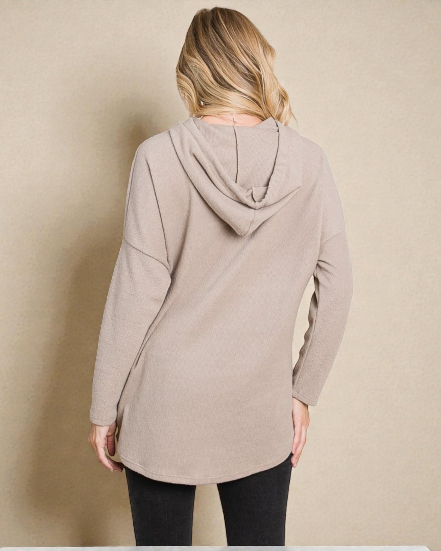 Person wearing a beige hooded jacket against a plain background