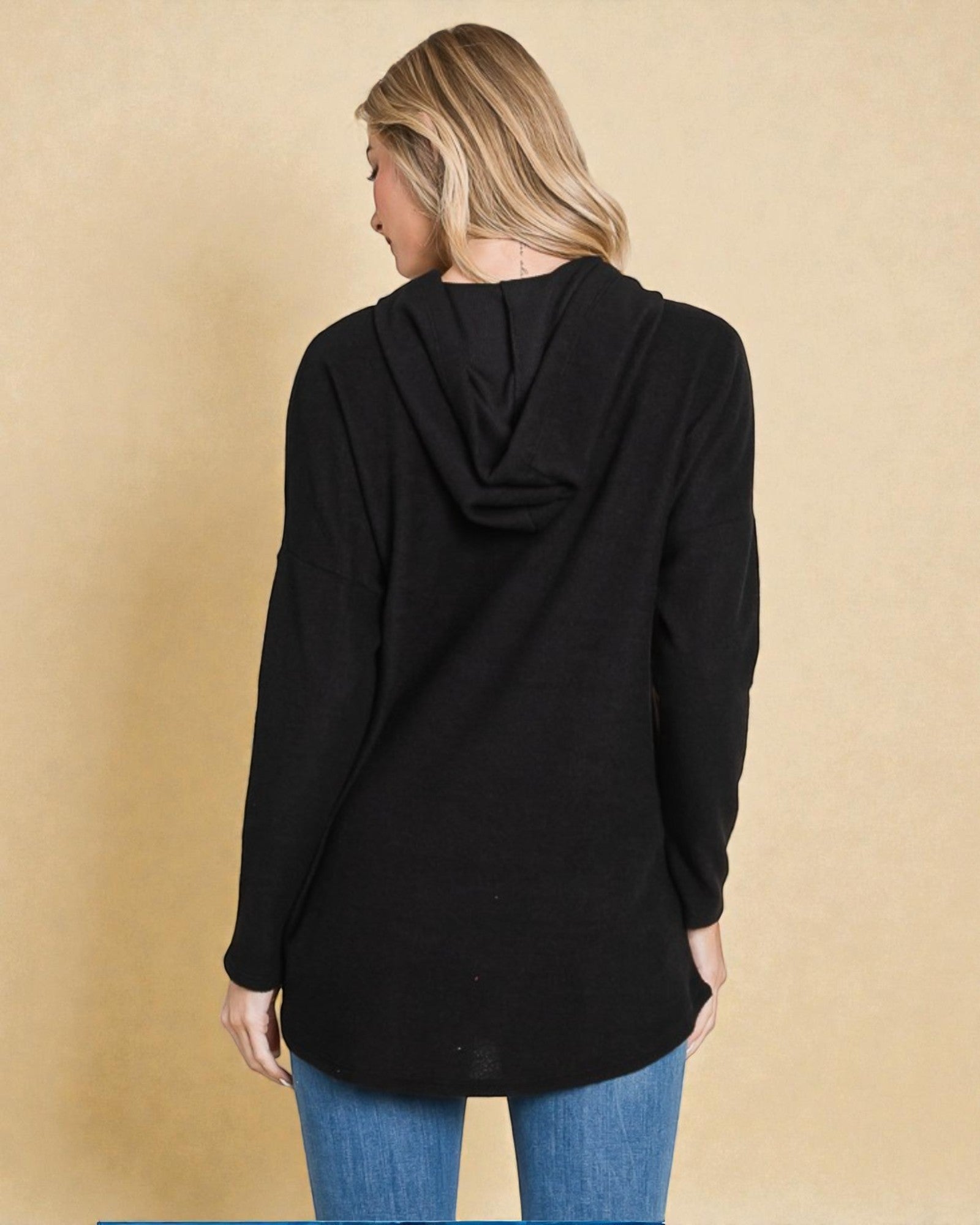 Person wearing a black hoodie with a beige background