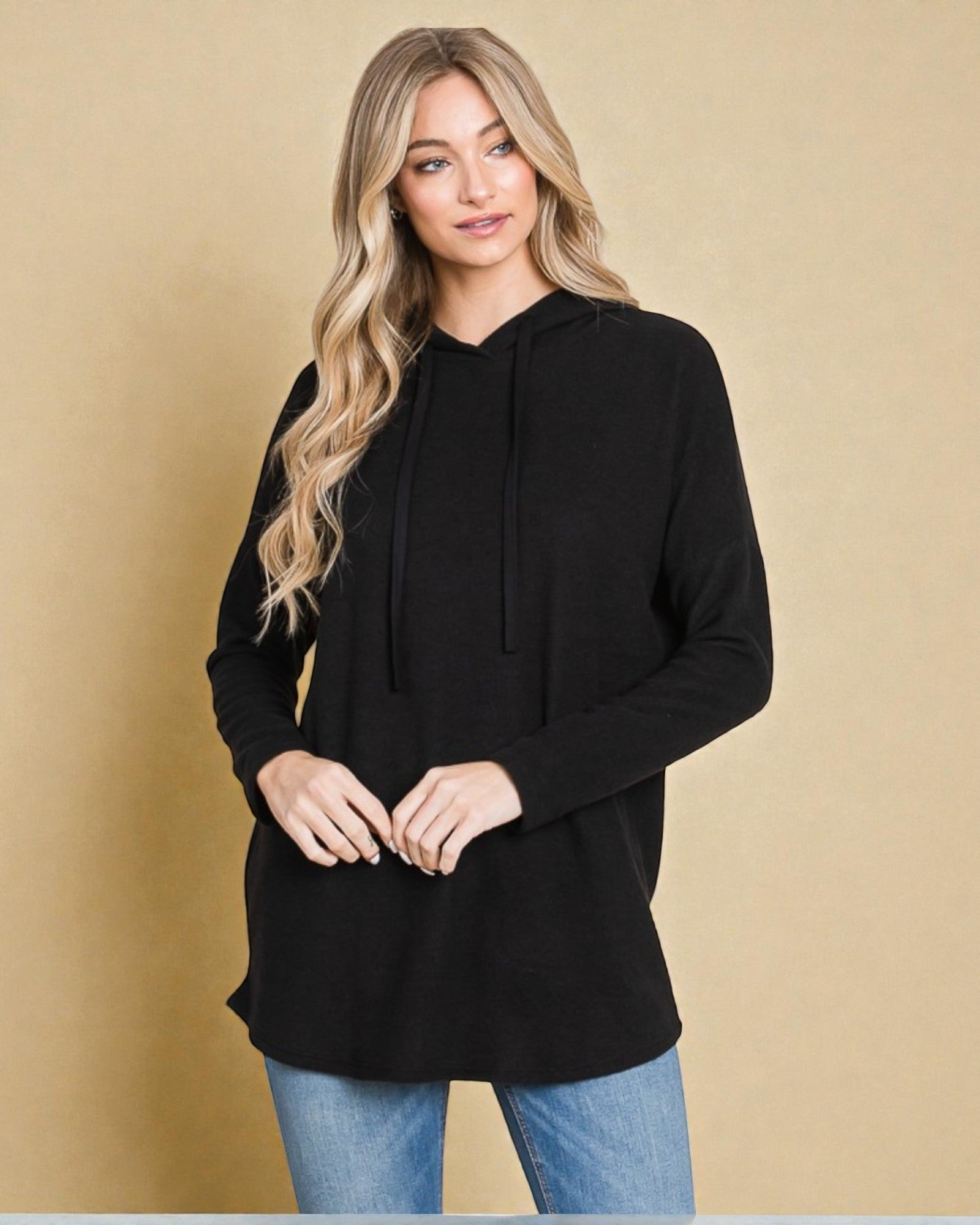 Woman wearing a black hoodie against a beige background