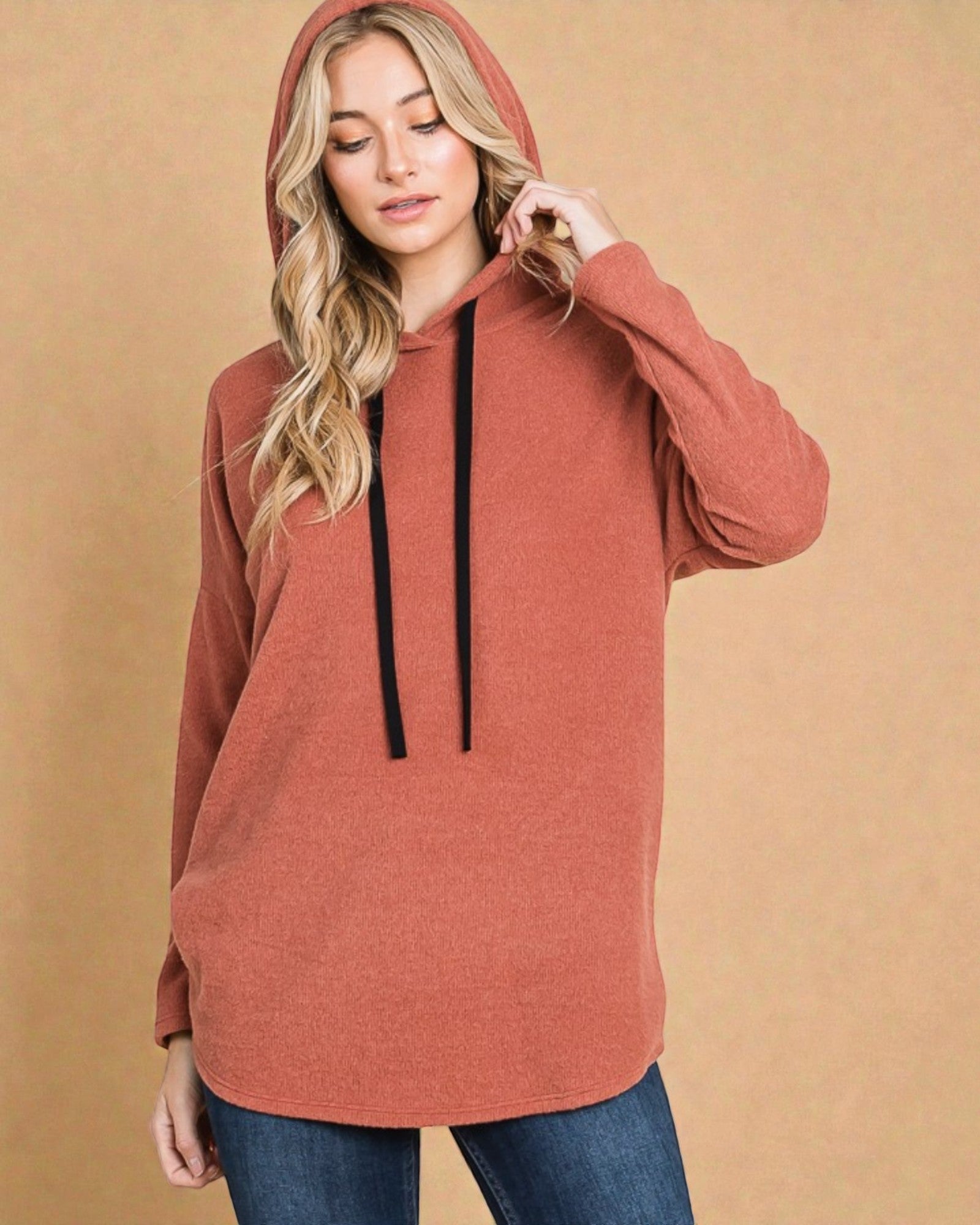 Woman wearing a rust-colored hoodie against a beige background