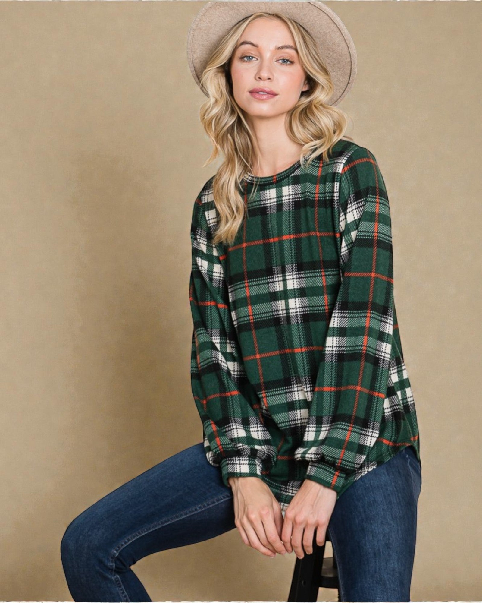 Woman wearing a green plaid shirt and jeans against a beige background