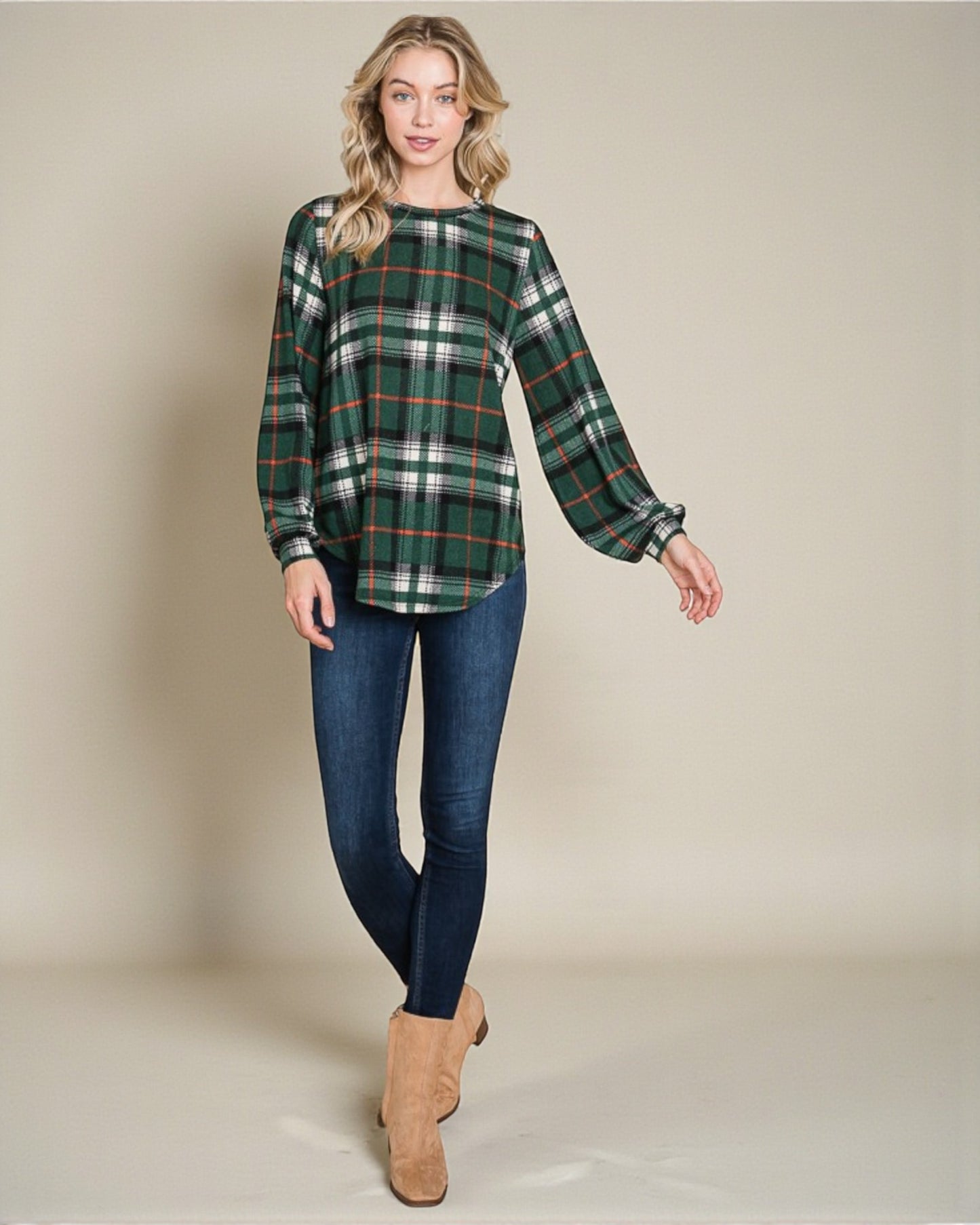 Woman wearing a green plaid shirt and blue jeans on a beige background