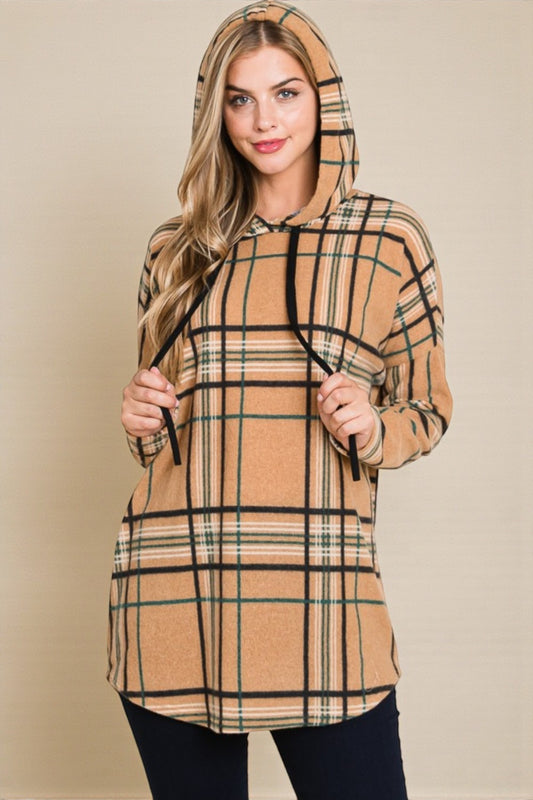 Woman wearing a beige and black plaid hoodie against a beige background