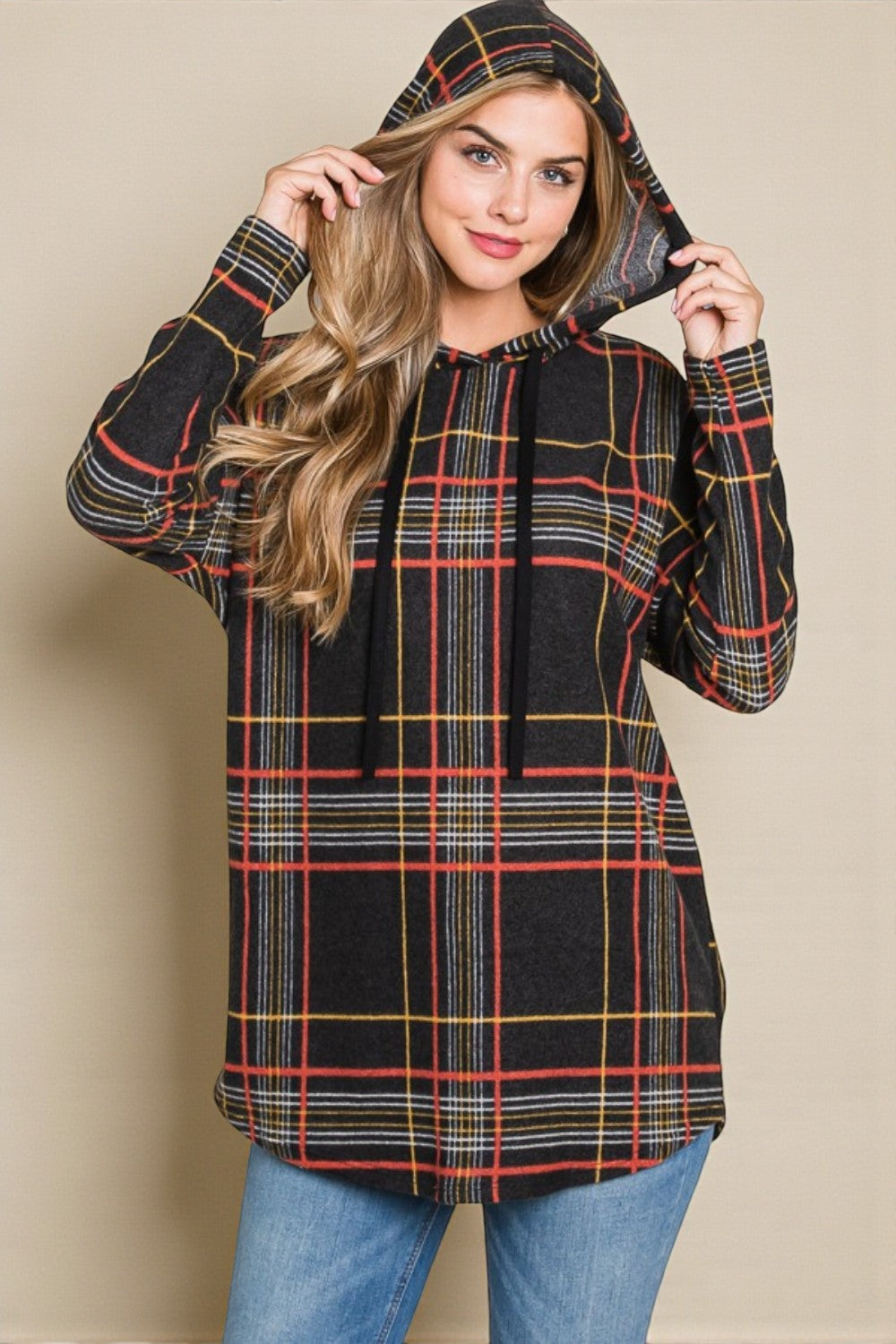 Woman wearing a plaid hoodie against a beige background