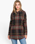 A woman wearing a black long-sleeve hooded tunic top with a red, yellow, and white plaid pattern, paired with blue jeans, against a plain white background.