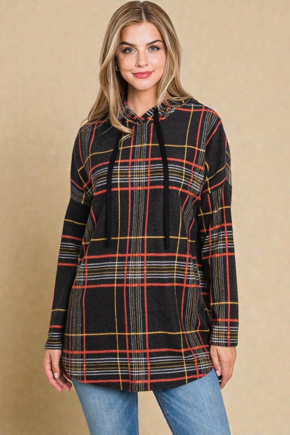 Woman wearing a plaid long-sleeve top against a beige background