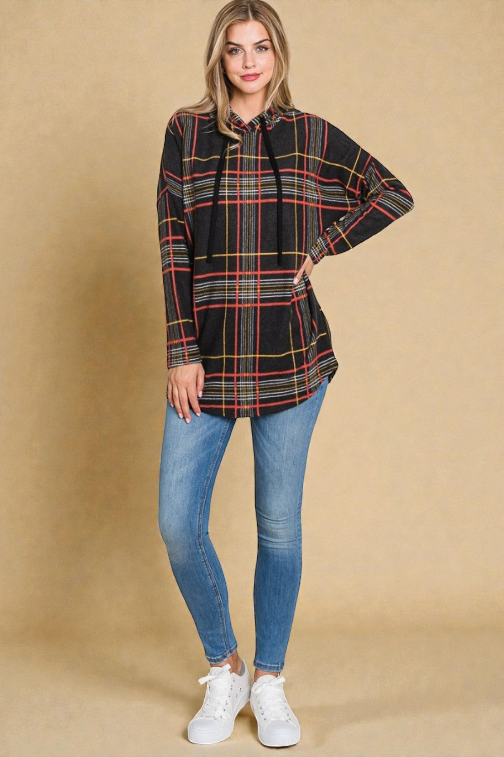 Woman wearing a plaid shirt and jeans against a beige background