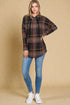 Woman wearing a plaid shirt and jeans against a beige background