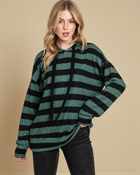 Woman wearing a green and black striped hoodie against a beige background