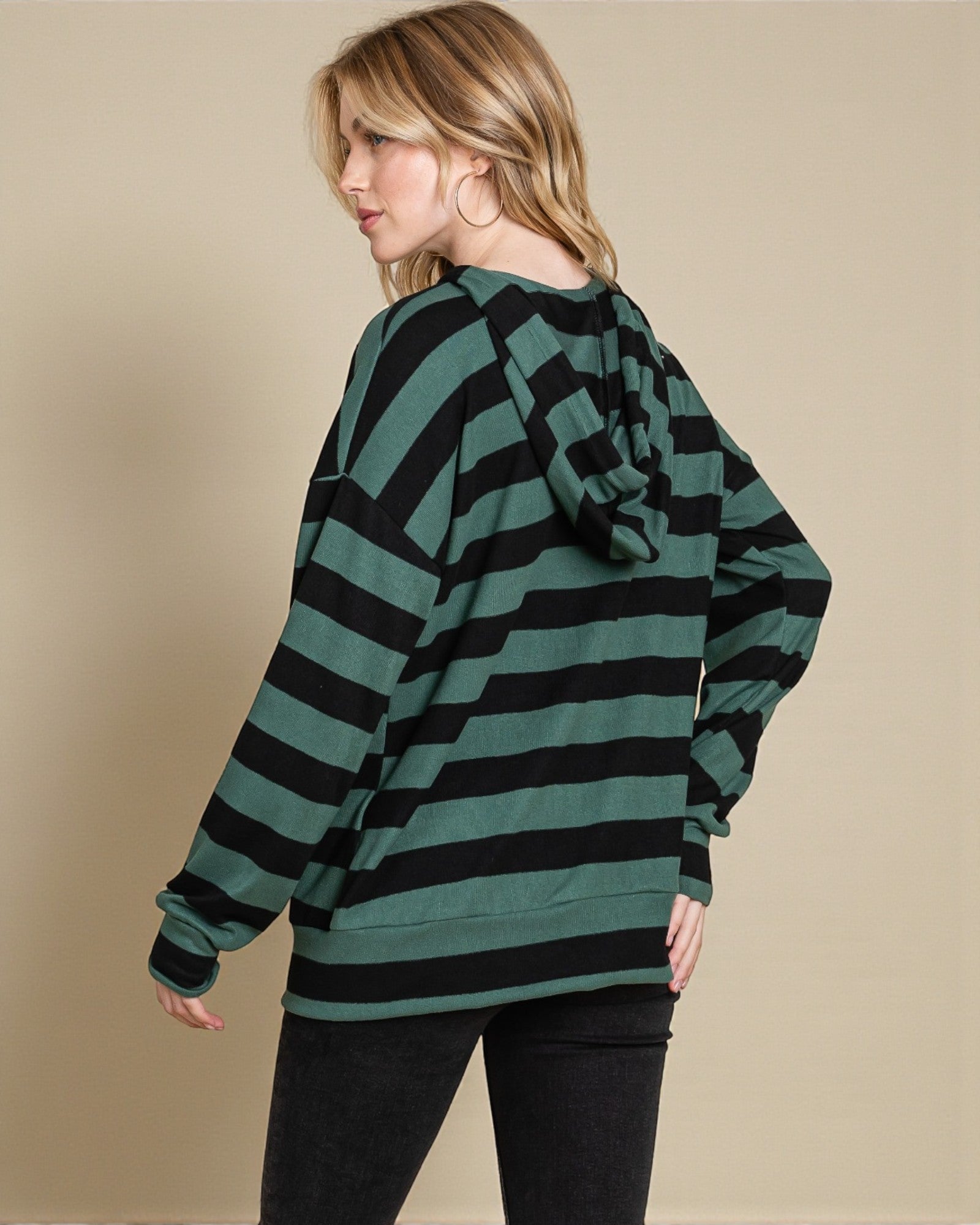 Woman wearing a green and black striped sweater against a beige background