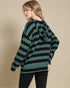 Woman wearing a green and black striped sweater against a beige background