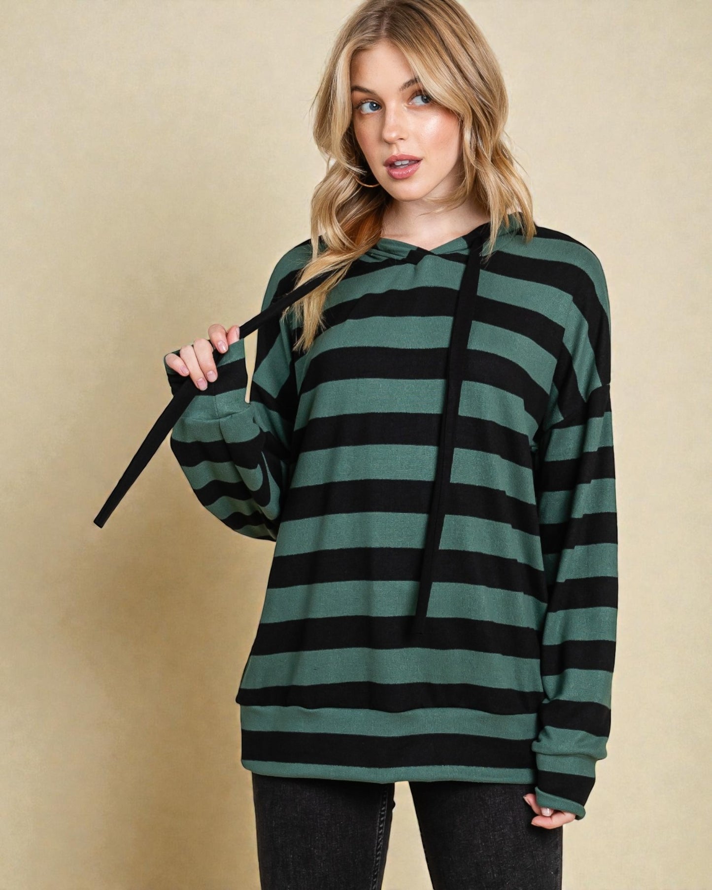 Woman wearing a green and black striped hoodie against a beige background