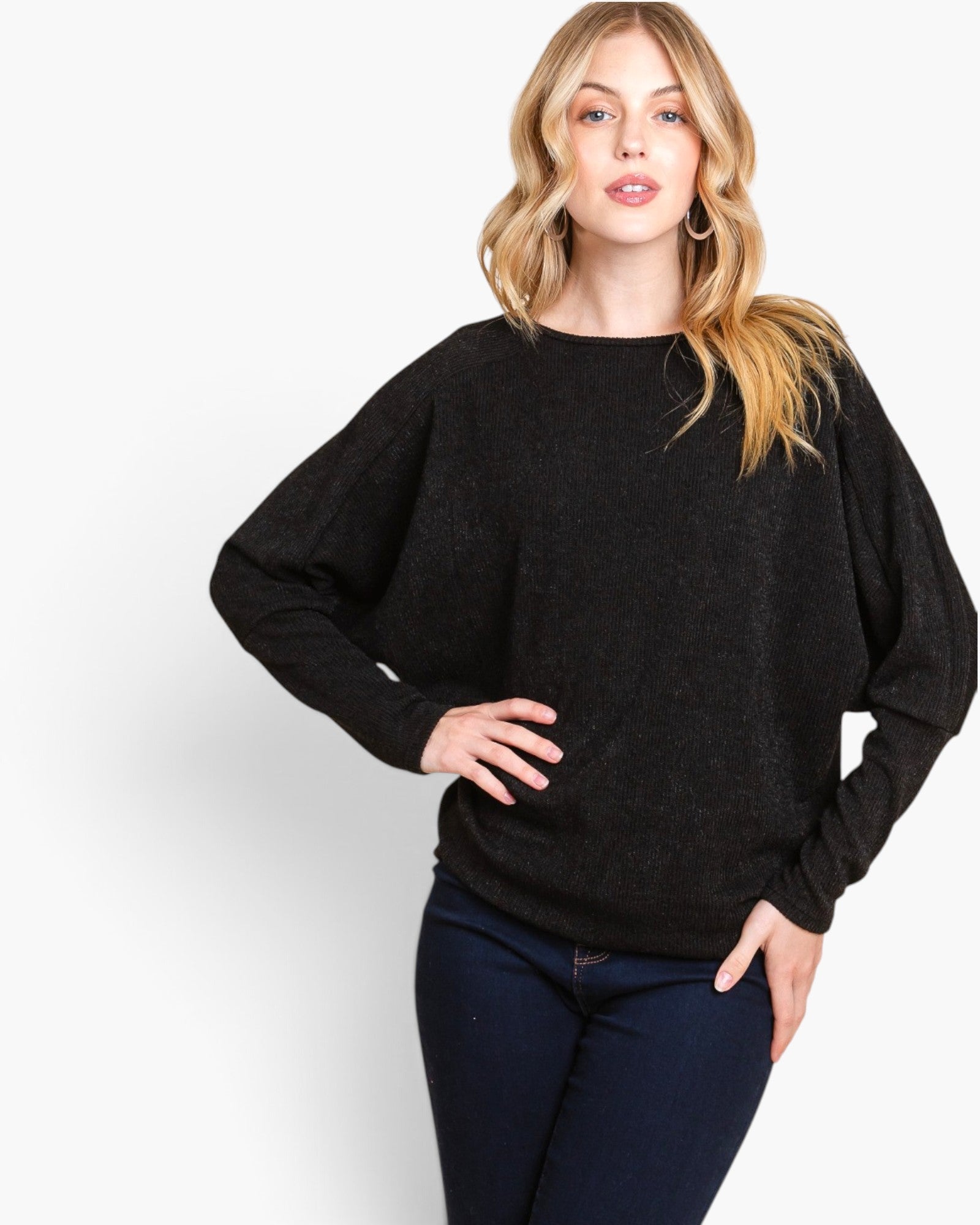A woman modeling a black long-sleeve knit sweater with a relaxed fit and elbow-length sleeves, paired with dark blue jeans, against a plain white studio background.