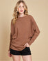 Woman wearing a brown sweater and black shorts on a beige background
