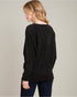 Woman wearing a black sweater against a plain background