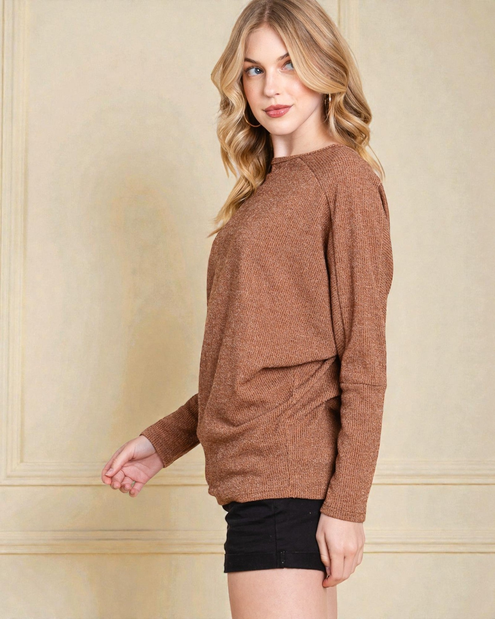 Woman wearing a brown sweater against a beige wall