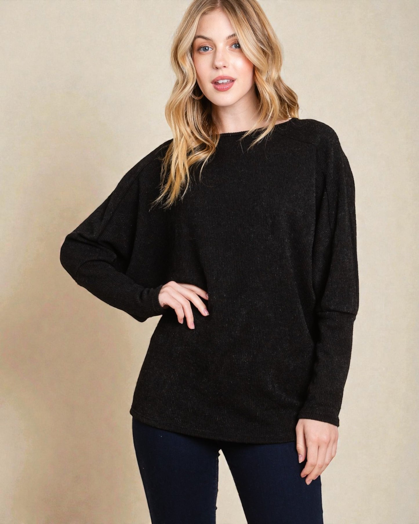 Woman wearing a black sweater against a beige background