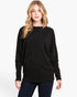 A woman modeling a black long-sleeve knit sweater with a wide boat neckline, photographed against a clean white studio background.