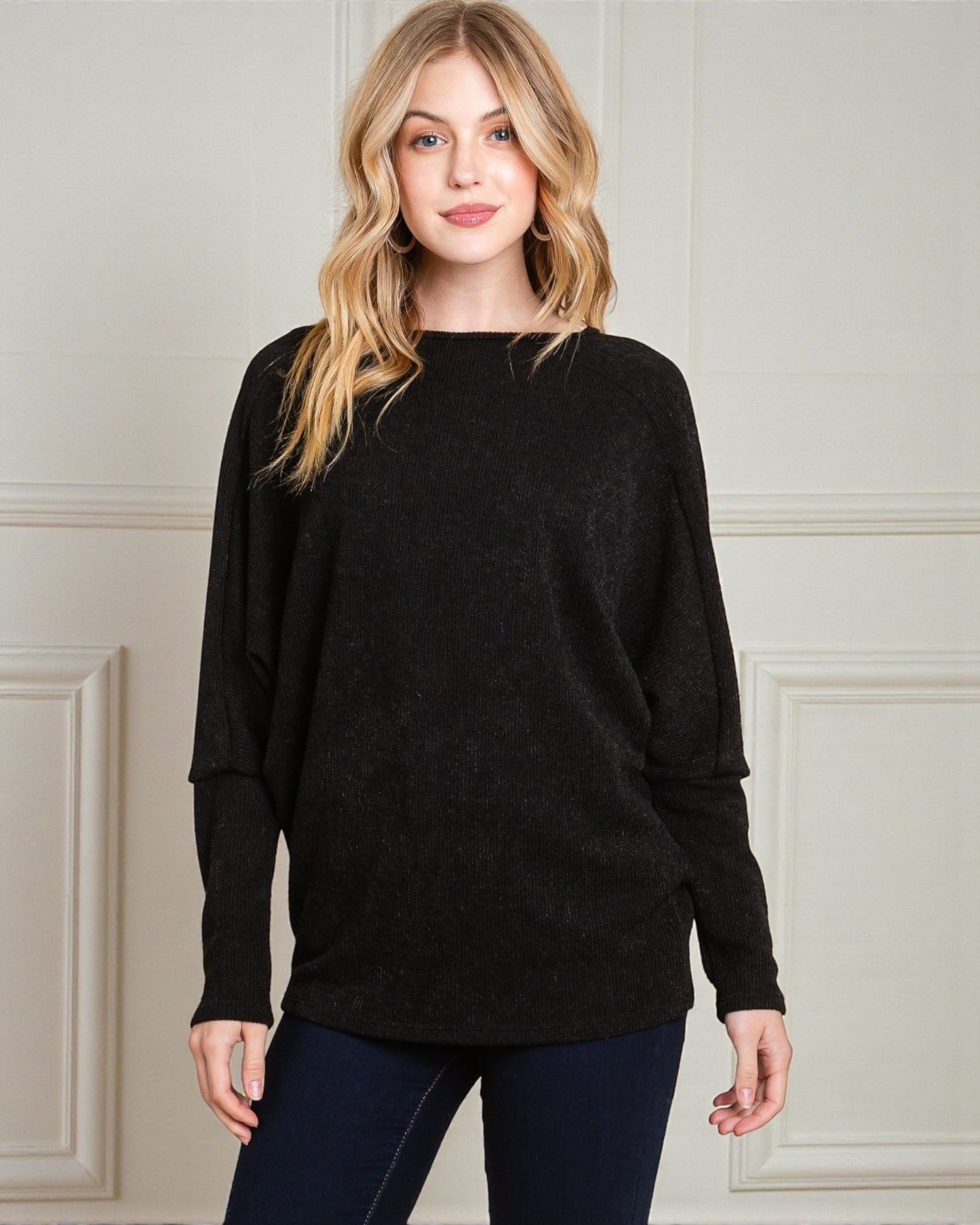 Woman wearing a black sweater against a neutral background