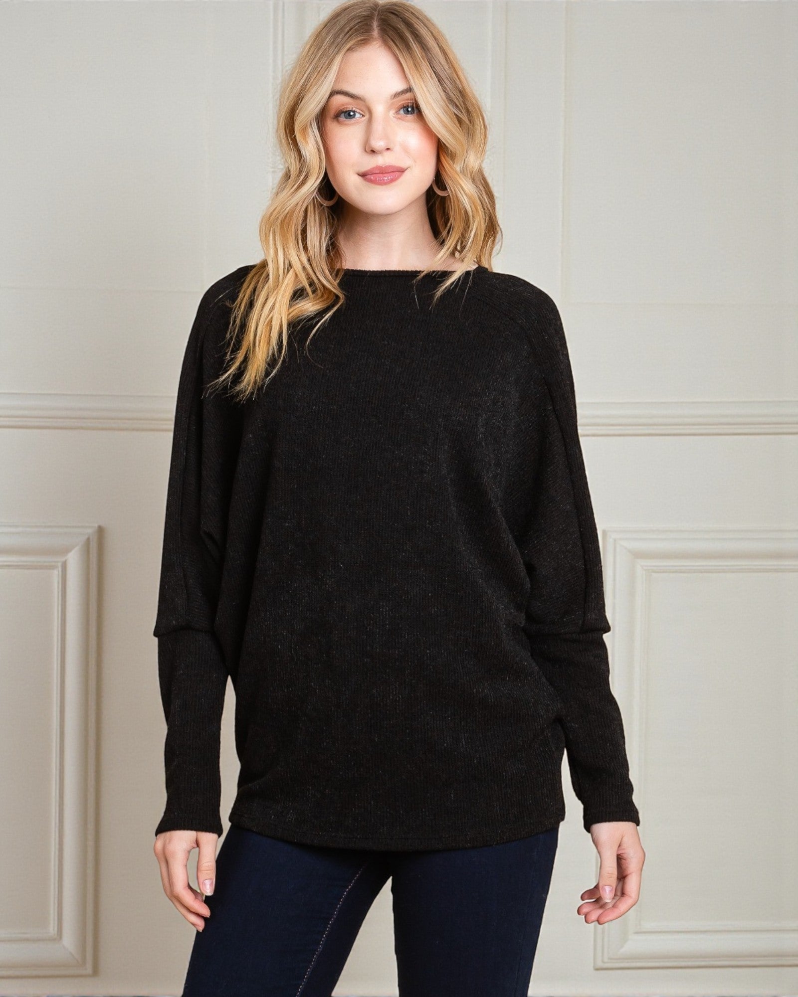 Woman wearing a black sweater against a neutral background