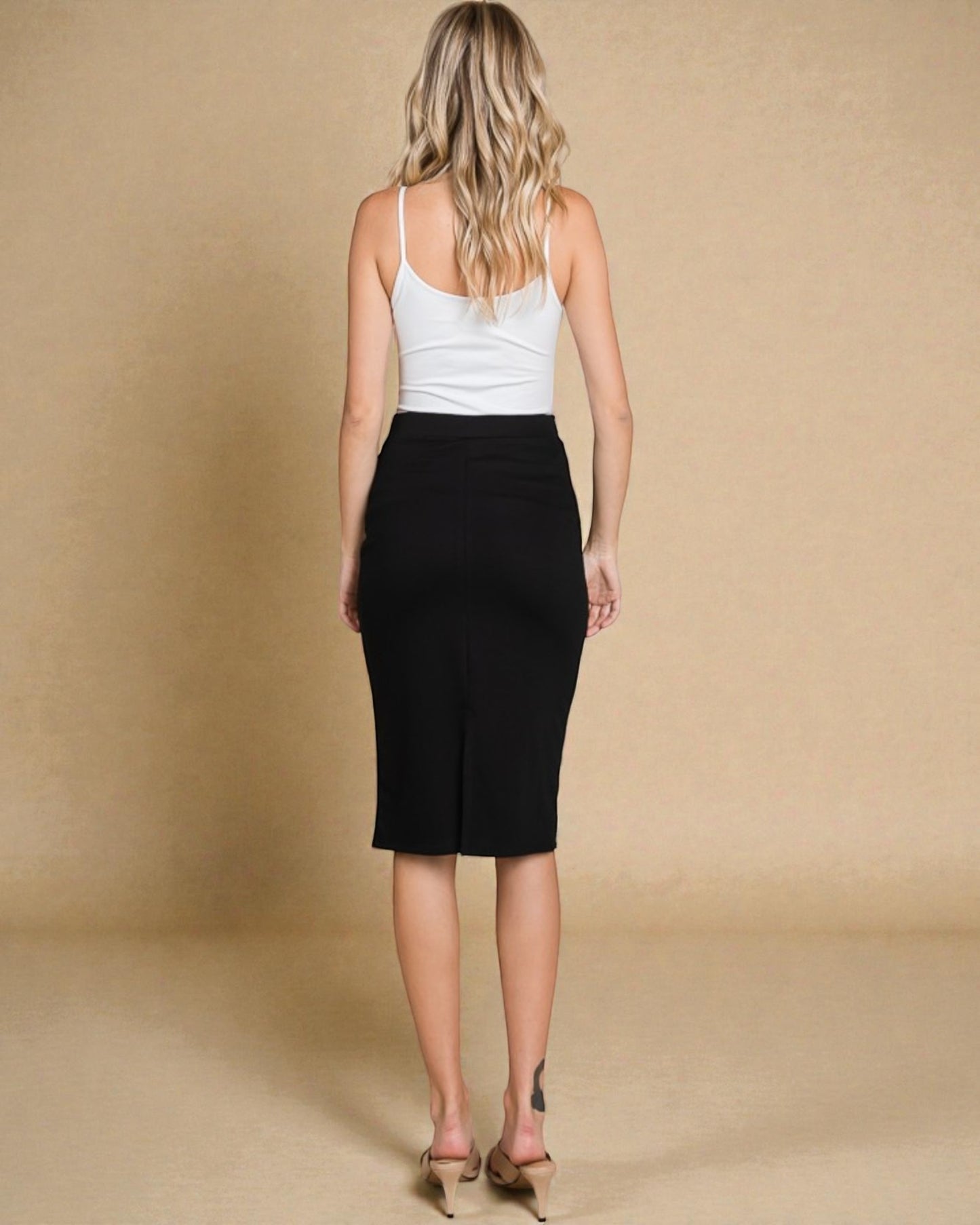 Woman wearing a white tank top and black skirt on a beige background