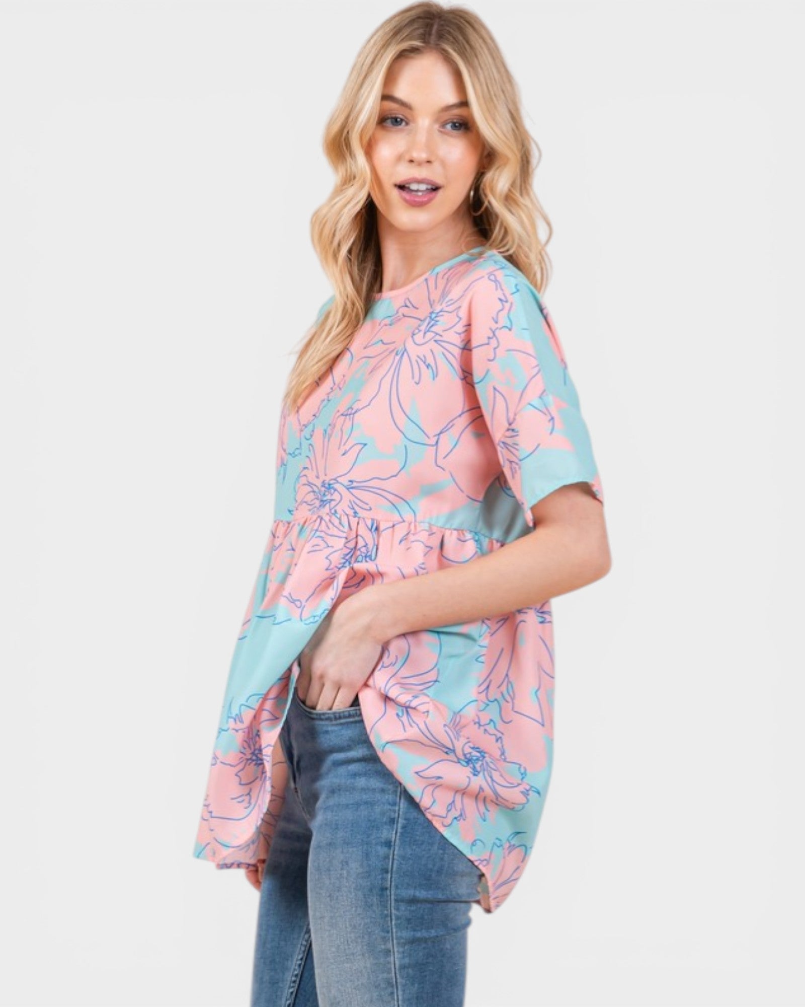 Woman wearing a pink and blue floral blouse with jeans on a white background