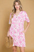 Woman wearing a pink floral dress holding a woven bag against a beige background