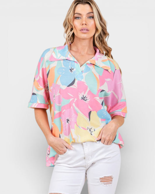 Woman wearing a colorful floral shirt with white pants on a plain background