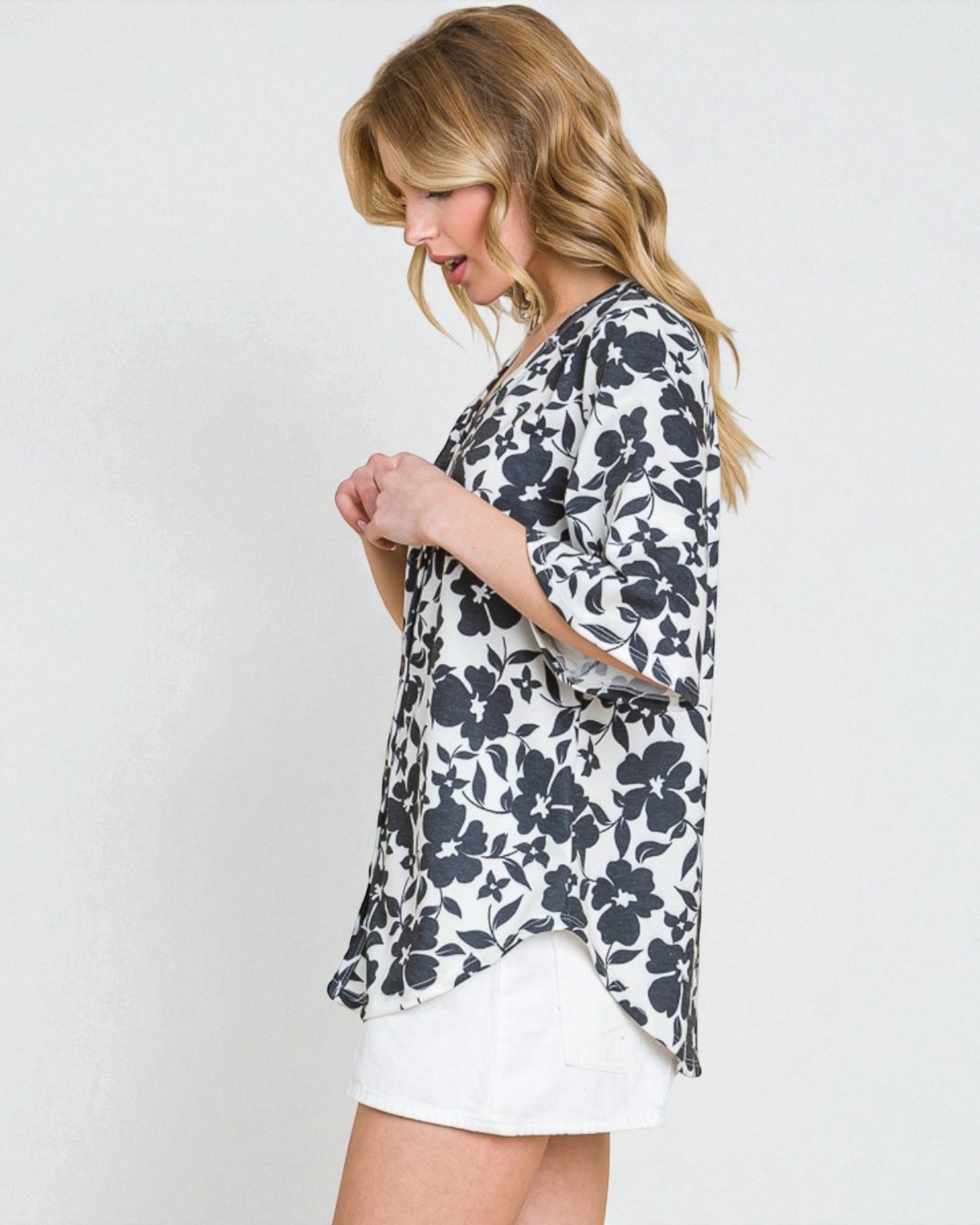 Woman wearing a floral kimono-style garment against a plain background