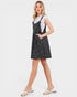 Woman wearing a black polka dot pinafore dress over a white shirt on a white background