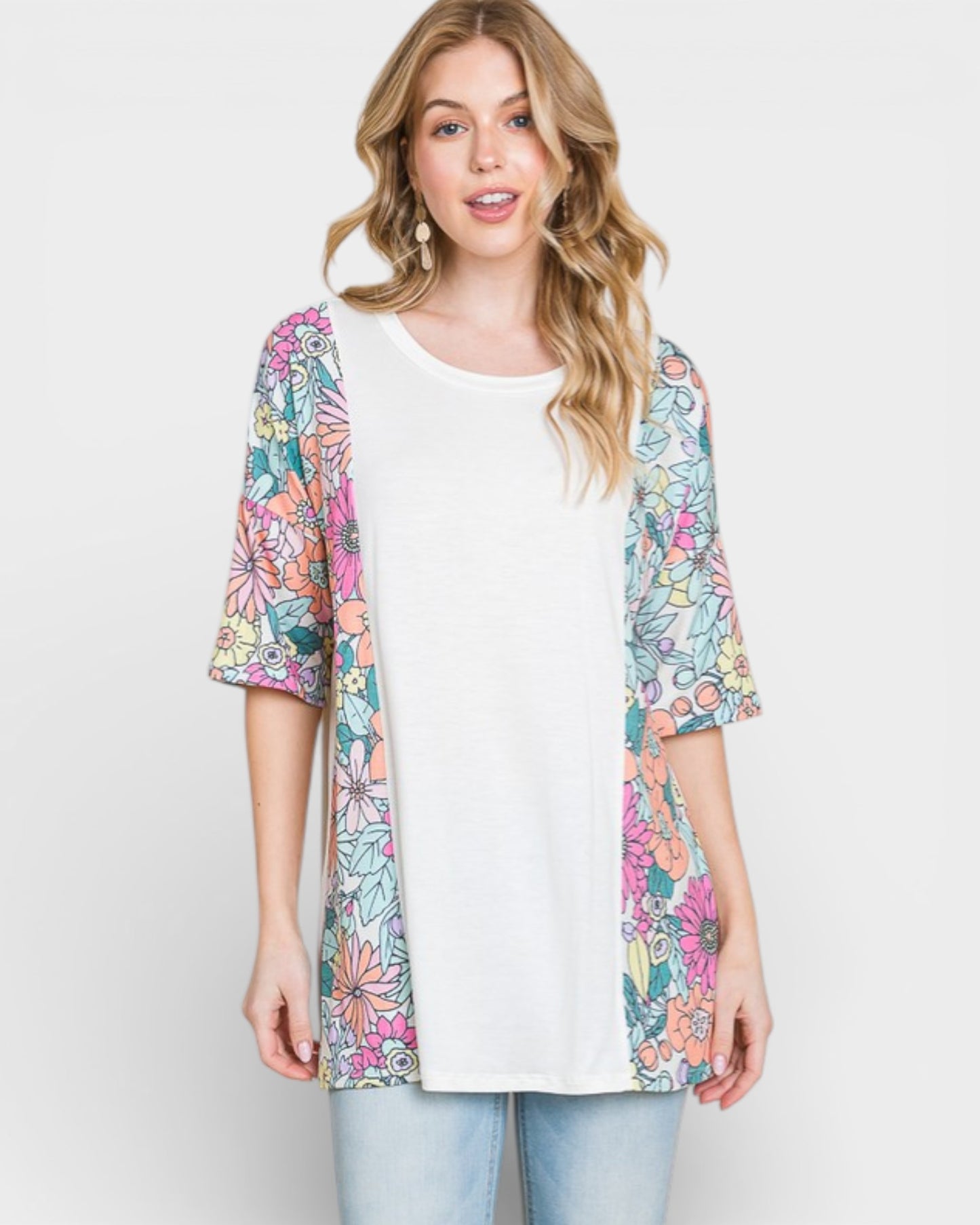 Woman wearing a colorful floral cardigan over a white shirt on a light gray background