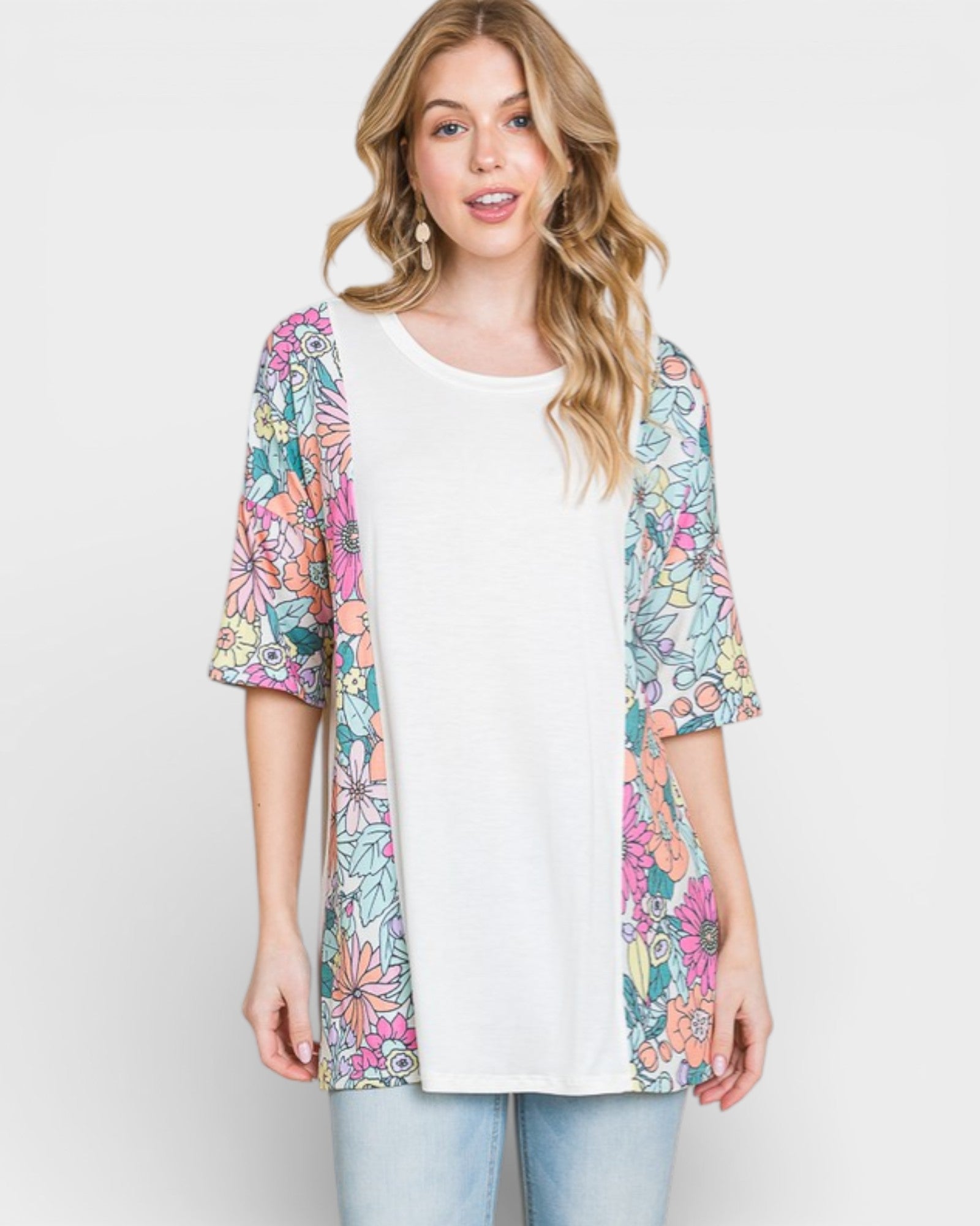Woman wearing a colorful floral cardigan over a white shirt on a light gray background