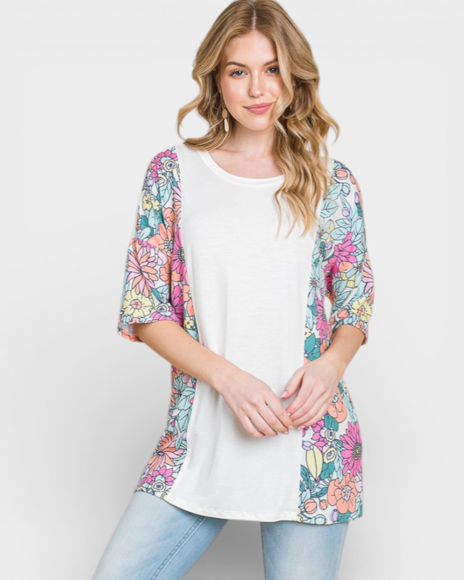 Woman wearing a colorful floral cardigan over a white top on a light gray background