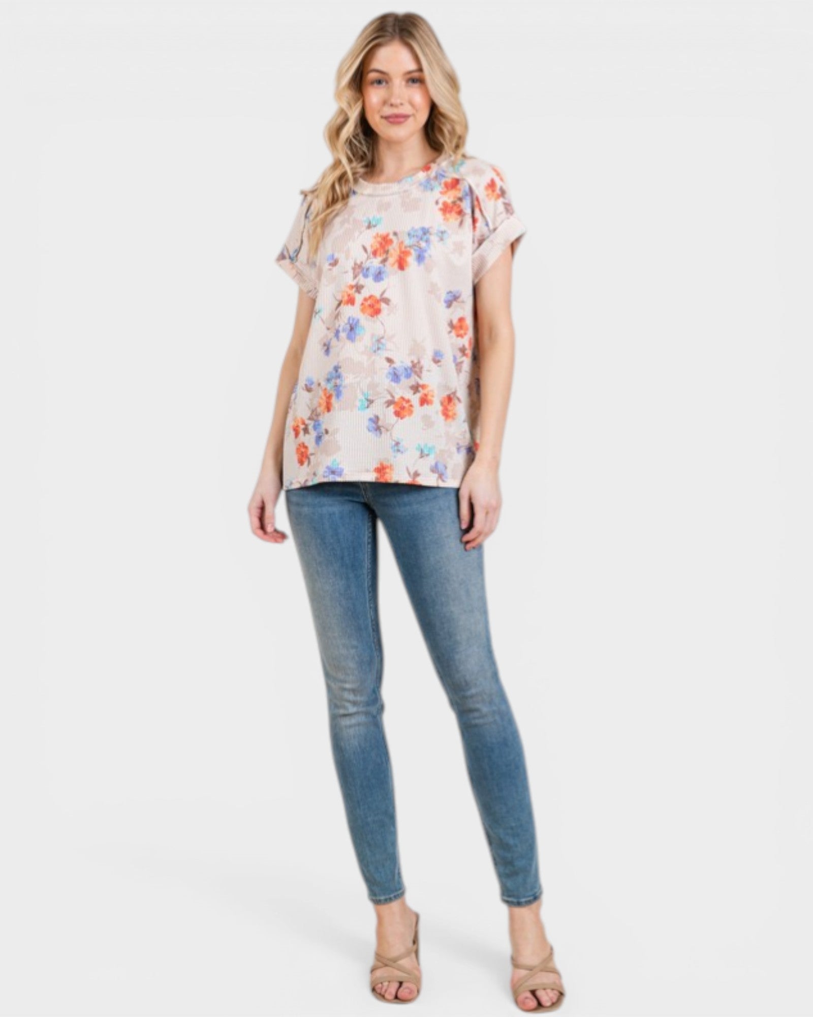 Woman wearing a floral top and blue jeans on a white background